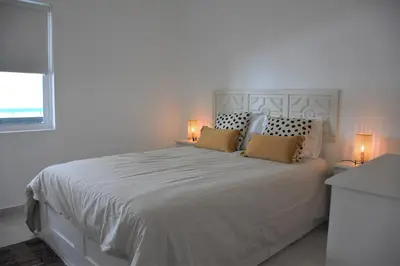 a white bedroom with a large white bed with two lamps at Vilamoura Neptuno Apartment in Vilamoura