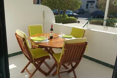 a wooden table with green chairs and a bottle of wine at Charming Beachside Apartment- The Perfect Getaway! in Albufeira