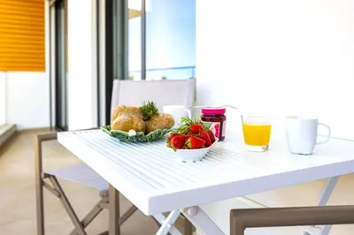 a white table with a bowl of fruit and a glass of orange juice at Luxury 3-Bed Penthouse with Ocean Views, Terrace & Pool in Quarteira