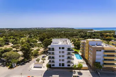 an aerial view of a building and the ocean at Luxury 3-Bed Penthouse with Ocean Views, Terrace & Pool in Quarteira