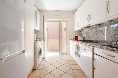 a kitchen with white cabinets and a washer and dryer at Coastal Golf by Seareen in Vilamoura