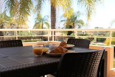a table with a plate of food and orange juice at Coastal Greens by Seareen in Quarteira