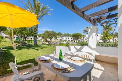 a table with chairs and an umbrella on a patio at Balaia Golf Poolside Retreat - Superior 2 bed villa in Albufeira