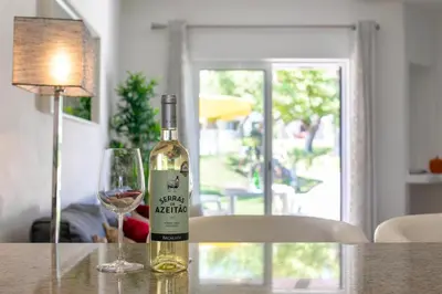 a bottle of wine sitting on a table with a glass at Balaia Golf Poolside Retreat - Superior 2 bed villa in Albufeira