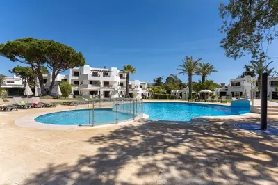 a swimming pool in a resort with palm trees and buildings at Balaia Golf Poolside Retreat - Superior 2 bed villa in Albufeira
