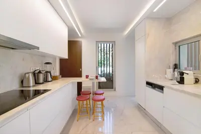 a kitchen with white cabinets and pink stools in it at Sweet Home Albufeira in Albufeira