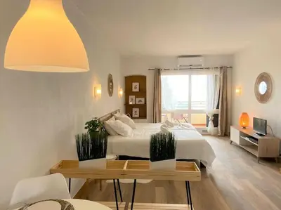 a white bedroom with a bed and a table and a window at Studio with great sea view, near the beach, with AC and pools in Albufeira