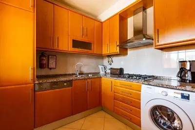 a kitchen with wooden cabinets and a washing machine at Casa Colina in Albufeira