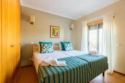 a bedroom with a bed with blue pillows and a window at Casa Colina in Albufeira