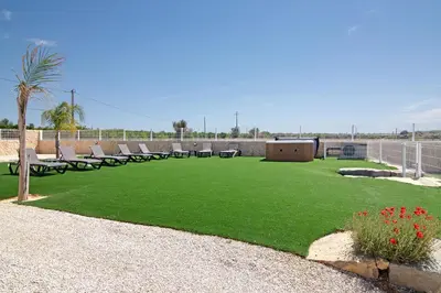 a large lawn with chairs and a fence and a field at Villa Flora in Algoz