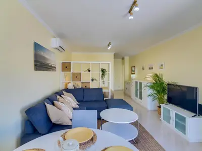a living room with a blue couch and tables at AL - Apartamento Falésia Terrace in Vilamoura