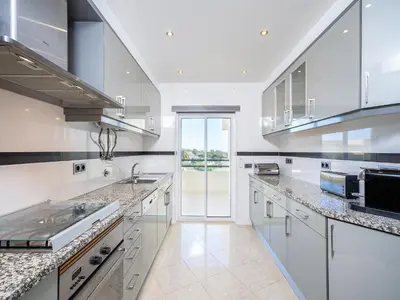 a kitchen with white cabinets and a large window at Luxury Penthouse wStunning Sea Views, walk to Galé Beach Albufeira in Albufeira