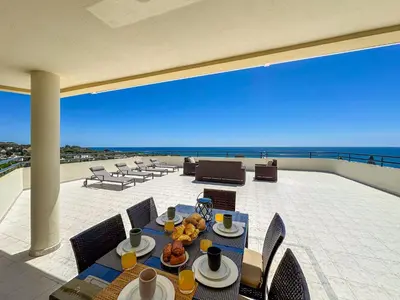 a table on a balcony with a view of the ocean at Luxury Penthouse wStunning Sea Views, walk to Galé Beach Albufeira in Albufeira