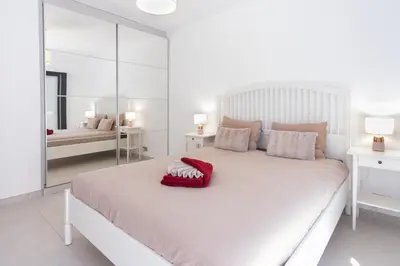 a bedroom with a large white bed with a red pillow on it at Vilamoura Marina Villa in Vilamoura