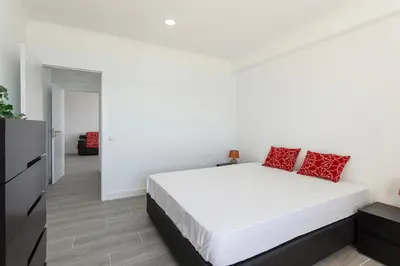 a white bedroom with a large white bed with red pillows at Quarteira SeaViews in Quarteira