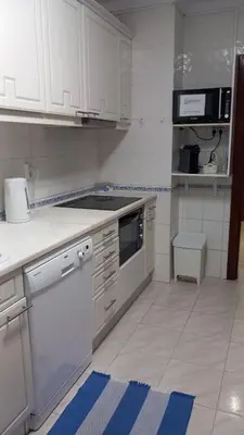 a kitchen with white appliances and blue and white cabinets at Quarteira Apartamento T2 - Oceanides in Quarteira