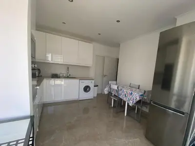 a kitchen with white cabinets and a washer and dryer at Guest House in Faro