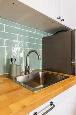a kitchen with a stainless steel sink and blue tile at Casinha da Jade in Albufeira