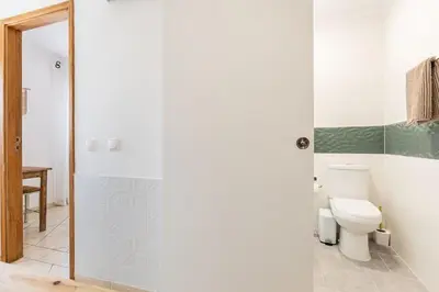 a bathroom with a toilet and a glass shower door at Casinha da Jade in Albufeira