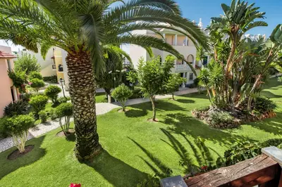 an image of a garden with palm trees at Spacious 3BR Apartment in Vilamoura Old Village with Rooftop BBQ, Pools & Panoramic Views in Quarteira
