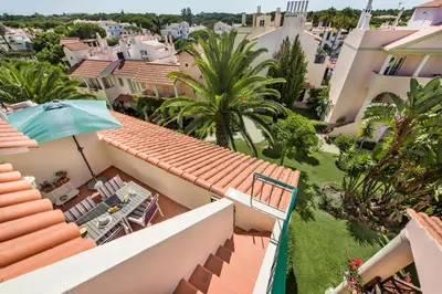 a view from the balcony of a house with an umbrella at Spacious 3BR Apartment in Vilamoura Old Village with Rooftop BBQ, Pools & Panoramic Views in Quarteira